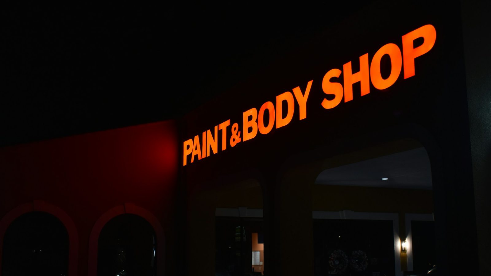Des lettres lumineuses orange sur une façade sombre, la nuit